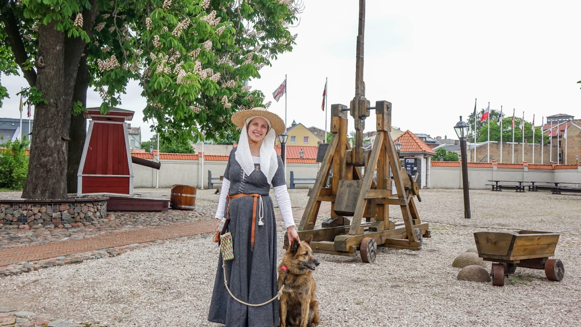 Darbiniece tērpā un ar suni pie Livonijas ordeņa pils